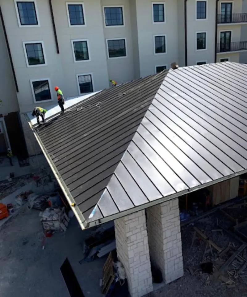 Crew installing standing seam metal roof panels on a commercial project in Northport